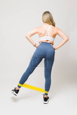 Photo for Beautiful girl working out and doing resistance band exercises  and working out her legs and booty at the gym - Royalty Free Image