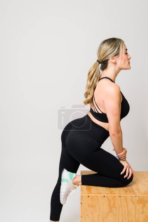 Téléchargez les photos : Femme caucasienne active avec un beau corps en forme à l'aide d'une boîte de saut à l'exercice pour son entraînement transversal à la salle de gym - en image libre de droit