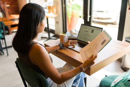 Foto de Mujer o estudiante buscando un nuevo trabajo y revisando su currículum o CV mientras está en la cafetería usando la zona wifi de la cafetería - Imagen libre de derechos