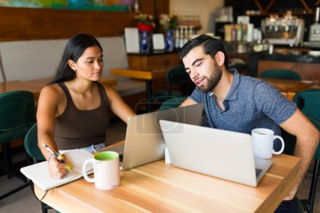 Téléchargez les photos : Les jeunes travailleurs indépendants au café parlent de leur entreprise en utilisant la zone wifi et en buvant du café - en image libre de droit
