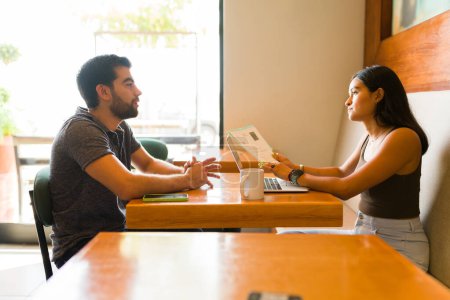 Foto de Mujer latina hablando con un hombre que solicita un nuevo trabajo mientras hace una entrevista de trabajo en la cafetería - Imagen libre de derechos
