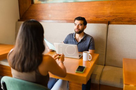 Téléchargez les photos : Homme attrayant souriant au café tout en faisant un entretien d'embauche avec une femme latine postuler pour un nouvel emploi - en image libre de droit