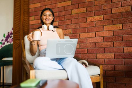 Photo for Cheerful woman freelancer smiling feeling happy while doing remote work using her laptop at a beautiful coffee shop - Royalty Free Image