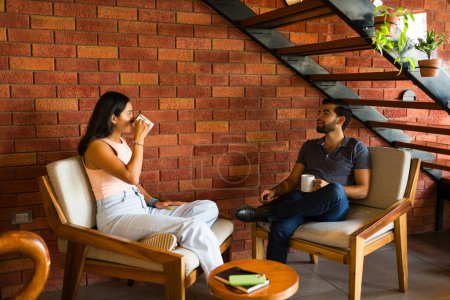 Téléchargez les photos : Jeune couple attrayant dans la vingtaine parlant lors d'un rendez-vous relaxant dans un café ou s'amusant en tant qu'amis - en image libre de droit