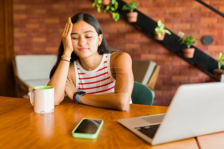 Téléchargez les photos : Fatigué jeune femme se sentant somnolent et épuisé tout en travaillant en freelance sur l'ordinateur portable - en image libre de droit
