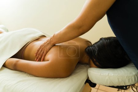 Photo for Mexican relaxed woman in her 20s lying resting at the massage table getting a back massage from a therapist - Royalty Free Image