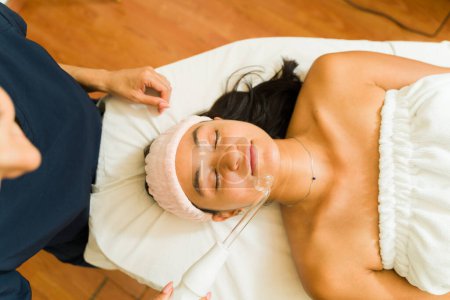 Foto de Atractiva mujer hispana haciendo una limpieza hidro facial o tratamiento para el cuidado de la piel en el spa de belleza wellness - Imagen libre de derechos