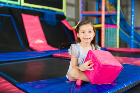 Photo for Adorable caucasian kid smiling while playing with foam cubes and having fun in the jumping center of the playground - Royalty Free Image