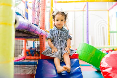 Photo for Cute caucasian child enjoying playing with kids in the indoor playground area and looking happy - Royalty Free Image