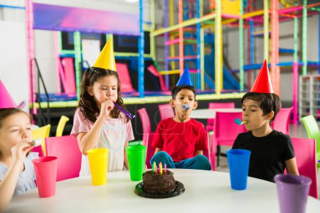 Foto de Grupo de niños felices listos para comer pastel durante una fiesta de cumpleaños con amigos divirtiéndose en el patio interior - Imagen libre de derechos
