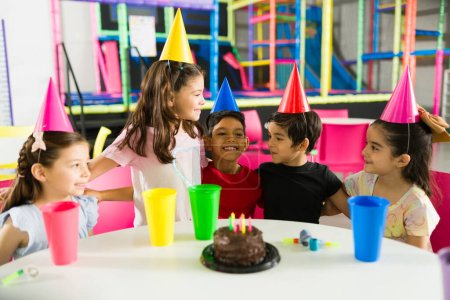 Foto de Emocionado grupo de niños riendo y divirtiéndose mientras celebran la fiesta de cumpleaños de un amigo en el patio interior - Imagen libre de derechos