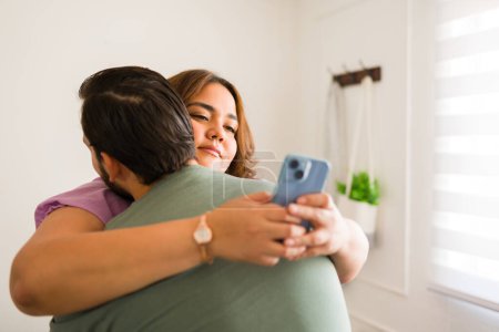 Foto de Pareja abrazar y tener problemas de engaño mientras novia mensajes de texto en el teléfono inteligente - Imagen libre de derechos