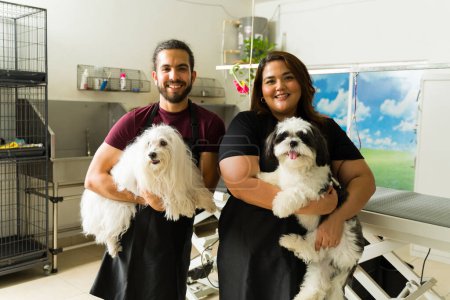 Photo for Attractive happy woman and man working as pet groomers smiling carrying two beautiful dogs at the dog spa - Royalty Free Image