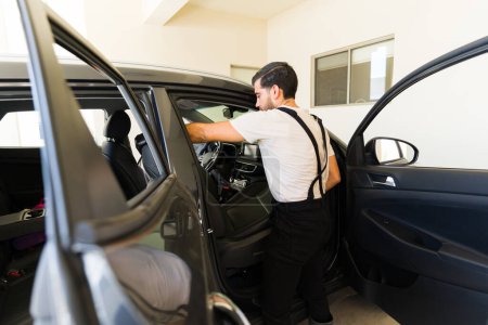 Téléchargez les photos : Jeune technicien enlever les sièges pour nettoyer les intérieurs de voiture au service de détail automatique - en image libre de droit