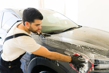 Photo for Young man working at the car wash washing car with soap and cloth - Royalty Free Image