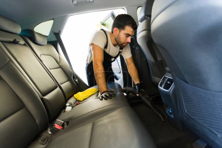 Téléchargez les photos : Mexicain homme nettoyage intérieur de voiture à l'aide d'aspirateur au lavage de voiture - en image libre de droit