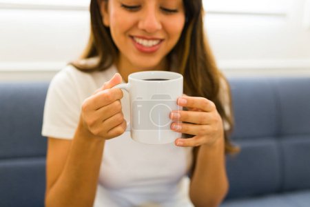 Téléchargez les photos : Joyeux mexicain jeune femme regardant heureux de boire du café sur un 11 oz blanc maquette tasse - en image libre de droit