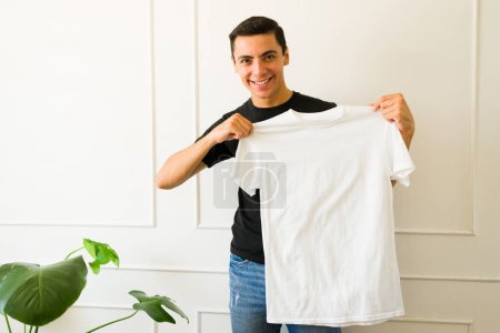 Téléchargez les photos : Heureux homme caucasien montrant un t-shirt blanc avec espace de copie pour un design - en image libre de droit