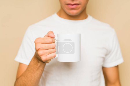 Téléchargez les photos : Homme caucasien buvant du café à l'aide d'une tasse blanche de 11 oz et d'un t-shirt maquillé pour un design de produit - en image libre de droit