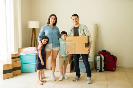Photo for Full length of a mexican family happy moving into a new house or apartment carrying boxes to unpack - Royalty Free Image