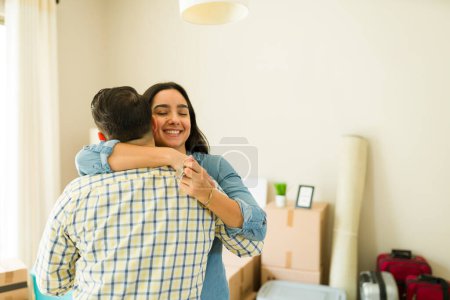 Photo for Attractive wife hugging her husband and celebrating getting a new mortgage credit to move into a new house together - Royalty Free Image