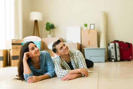Téléchargez les photos : Mari et femme détendus se reposant et rêvant de leur nouvelle maison tout en déballant et en emménageant - en image libre de droit