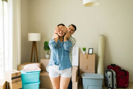 Foto de Feliz marido sorprendiendo a su hermosa esposa después de obtener un crédito hipotecario y comprar una nueva casa o apartamento - Imagen libre de derechos