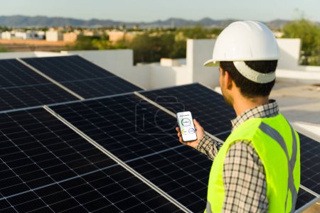 Foto de Vista trasera de un trabajador de ingeniería tomando fotos de la instalación de paneles solares y células fotovoltaicas en la azotea - Imagen libre de derechos