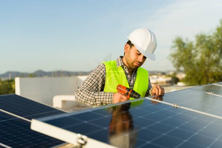 Foto de Hombre ingeniero trabajador con una perforación casco de seguridad mientras trabaja en instalaciones de paneles solares y energía limpia - Imagen libre de derechos