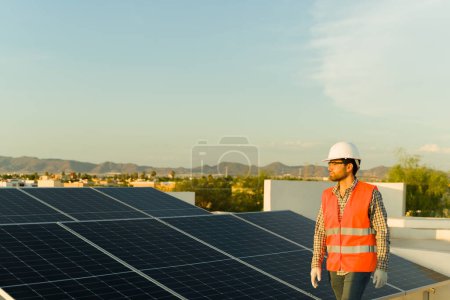 Foto de Joven guapo trabajando como ingeniero trabajando en una casa residencial instalando paneles solares y células fotovoltaicas - Imagen libre de derechos