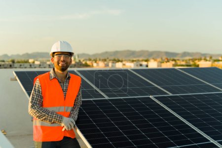 Foto de Ingeniero feliz sonriendo sintiéndose alegre por trabajar con energía verde limpia y sostenible instalando paneles solares en la azotea residencial - Imagen libre de derechos