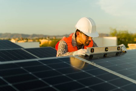 Foto de Ingeniero profesional con casco utilizando un nivelador mientras trabaja en instalaciones de paneles solares - Imagen libre de derechos