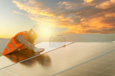 Foto de Ingeniero joven comprobando la instalación del panel solar en una casa residencial contra un hermoso cielo al atardecer - Imagen libre de derechos