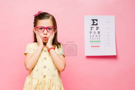 Photo for Surprised 7 year old little elementary kid suffering from nearsightedness looking excited while getting prescription glasses - Royalty Free Image