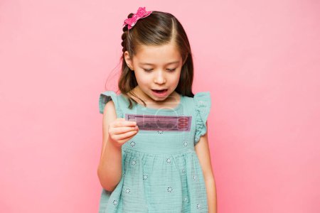 Photo for Cheerful cute little child looking excited and surprised getting her money allowance or earnings feeling happy - Royalty Free Image