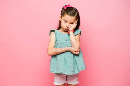 Téléchargez les photos : Ennuyé élémentaire petite fille se sentant ennuyé et contrarié ayant des problèmes d'enfant faire contact avec les yeux - en image libre de droit