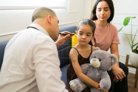Foto de Pediatra haciendo un examen y revisando el oído de un niño enfermo durante la visita al médico en casa - Imagen libre de derechos