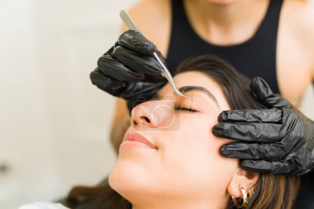 Photo for Beautiful woman at the beauty salon putting on eyelash extensions one by one with a professional beautician - Royalty Free Image