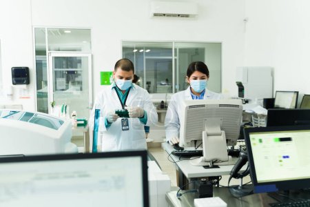 Foto de Químicos y técnicos de laboratorio que utilizan el equipo de laboratorio mientras trabajan en muestras de sangre y pruebas médicas - Imagen libre de derechos