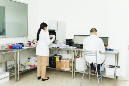 Foto de Químicos y técnicos de laboratorio vistos desde atrás usando el equipo de laboratorio mientras hacen pruebas médicas - Imagen libre de derechos