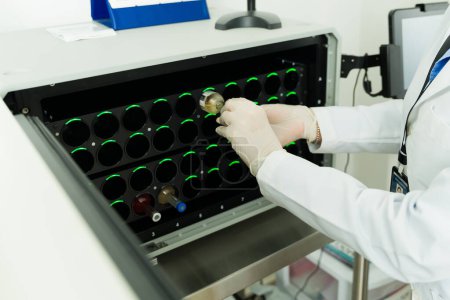 Téléchargez les photos : Technicien de laboratoire utilisant l'équipement de laboratoire et la machine de culture de mettre sur des échantillons de sang dans des éprouvettes travaillant dans la - en image libre de droit