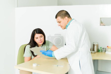 Foto de Químico profesional que pide una firma en un documento mientras está en el laboratorio médico listo para extraer sangre para pruebas médicas - Imagen libre de derechos