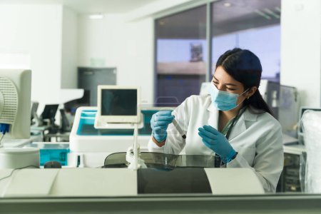 Téléchargez les photos : Joyeux jeune femme et chimiste utilisant l'équipement de laboratoire pour faire des tests médicaux à l'aide d'échantillons de sang - en image libre de droit