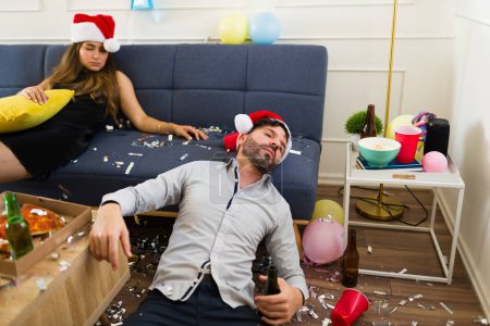 Téléchargez les photos : Homme caucasien évanoui ivre avec une femme latine dormir après avoir célébré une fête de nouvel an après avoir bu beaucoup d'alcool - en image libre de droit