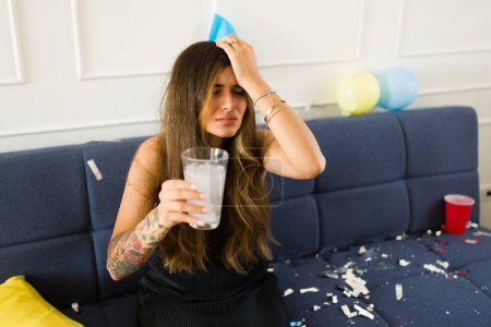 Upset sick young woman suffering a strong headache because of a bad hangover after a party drinking a lot of alcohol