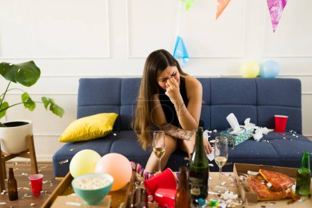 Photo for Depressed young woman crying regretting the night before after drinking a lot of alcohol during a party and crying feeling sad - Royalty Free Image