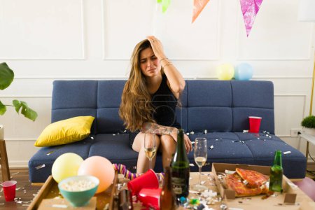 Photo for Hungover mexican woman with a headache feeling nausea and sick after drinking a lot of alcohol after a party - Royalty Free Image
