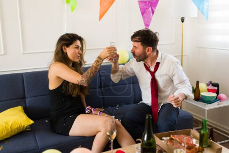 Téléchargez les photos : Joyeux jeune femme et l'homme acclamant tout en buvant des coups de tequila l'air ivre et s'amuser ensemble à une fête - en image libre de droit