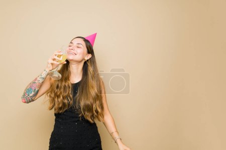 Foto de Mujer hispana alegre sonriendo bebiendo champán y mucho alcohol llevando una fiesta y celebrando en el estudio con espacio para copiar - Imagen libre de derechos