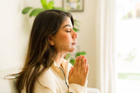Téléchargez les photos : Belle jeune femme spirituelle latine récitant une prière de la Bible et priant avec un style de vie religieux - en image libre de droit